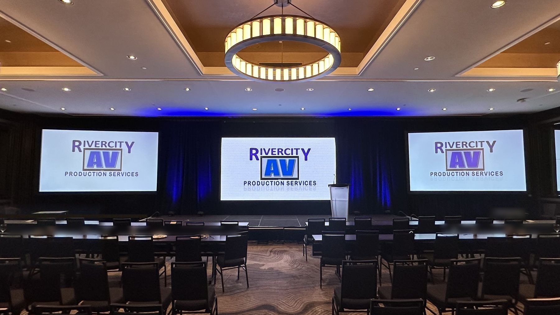 Ballroom with three screens showing Rivercity AV branding